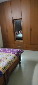 a bedroom with a bed with a mirror and wooden cabinets at Service Apartment Near Rameshwaram Cafe Brookefield in Bangalore