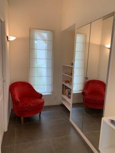 Habitación con 2 sillas rojas y espejo. en Au Coeur de la Provence, en Éguilles