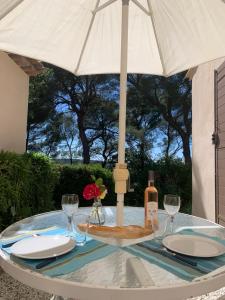 una mesa con una sombrilla blanca y una botella de vino en Au Coeur de la Provence, en Éguilles