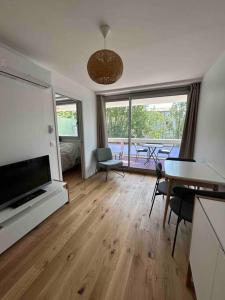 a living room with a television and a table with chairs at Superbe appartement, terrasse, accès direct RER in Massy +15 photos