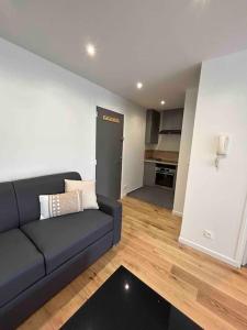 ein Wohnzimmer mit einem schwarzen Sofa und einer Küche in der Unterkunft Superbe appartement, terrasse, accès direct RER in Massy