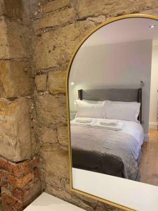 a mirror reflecting a bed in a stone wall at The Suite Apartment @3 in Barnsley