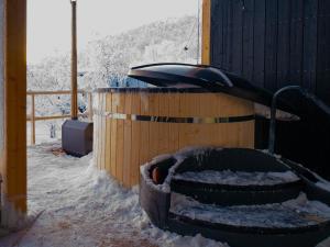 un neumático está cubierto de nieve junto a un edificio en Sunrise View Lapland, Sky View Bedroom & Hot Tub en Kilpisjärvi
