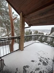 a snow covered deck with a fence and a tree at Radikiai House 