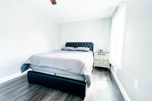 a white bedroom with a bed with a black headboard at The Ashland Manor 4BR in Niagara Falls