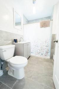 a white bathroom with a toilet and a shower at The Ashland Manor 4BR in Niagara Falls