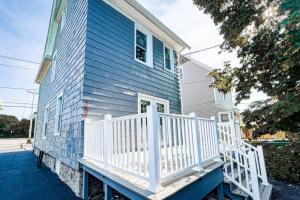 una casa azul con una barandilla blanca en un porche en The Ashland Manor 4BR en Niagara Falls