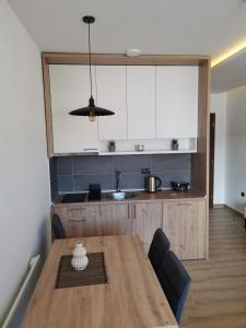 a kitchen with a wooden table and a kitchen with white cabinets at Harmony, Residence Hill A85 in Kopaonik