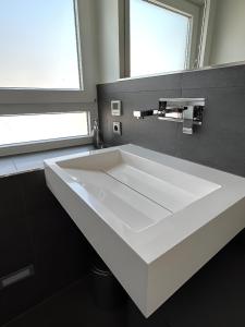 La salle de bains est pourvue d'un lavabo blanc et d'un miroir. dans l'établissement Rooftop Living inkl Homeoffice bis 4 Personen, à Friedrichshafen
