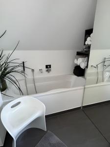ein weißes Bad mit einer weißen Badewanne und einem Stuhl in der Unterkunft Rooftop Living inkl Homeoffice bis 4 Personen in Friedrichshafen