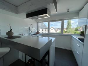 une cuisine avec comptoirs blancs et une grande fenêtre dans l'établissement Rooftop Living inkl Homeoffice bis 4 Personen, à Friedrichshafen