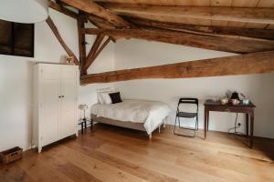 a bedroom with a bed and a desk and wooden ceilings at À l'orée du Cagire in Juzet-dʼIzaut