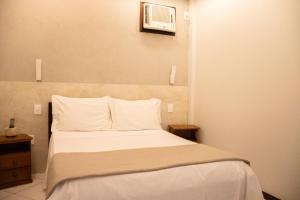 ein Schlafzimmer mit einem Bett mit weißer Bettwäsche und einer Mikrowelle in der Unterkunft Pousada Farol dos Borbas in Abraão