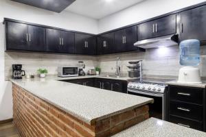 a kitchen with black cabinets and a counter top at Sol de Media Noche Jalisco in Sayula