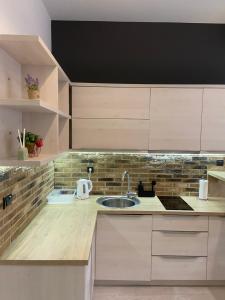 uma cozinha com armários brancos e um lavatório em Boulevard Apartments em Saraievo