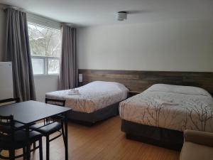 a hotel room with two beds and a table at Auberge Morritt in Mont-Tremblant