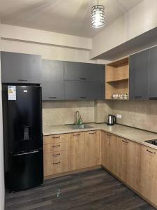 a kitchen with a black refrigerator and wooden cabinets at Апартамент Армад Цахкадзоре in Tsaghkadzor