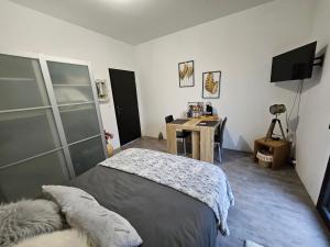Schlafzimmer mit einem Bett, einem Schreibtisch und einem TV in der Unterkunft Les ateliers 