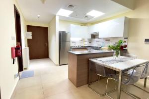 a large kitchen with a table and a refrigerator at Azizi Luxurious 1 Bed Room apartment, Near Metro, Fully Furnished in Dubai
