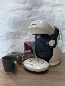a coffee maker and cups on a wooden table at Oranuisce Thatch Cottage Ballyvaughan in Ballyvaughan