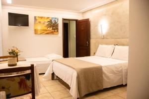 a hotel room with two beds and a table at Pousada Farol dos Borbas in Abraão