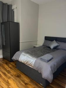 a bedroom with a bed and a black dresser at 3 Bedroom Apartment in London