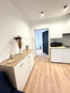 a kitchen with white cabinets and a wooden floor at Apartament SASANKA in Kudowa-Zdrój