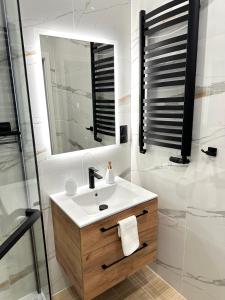 a white bathroom with a sink and a mirror at Apartament SASANKA in Kudowa-Zdrój