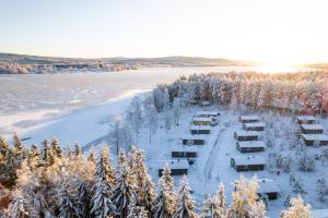 an aerial view of a lodge in the snow next to a river at Björnbyn Stugby in Råda