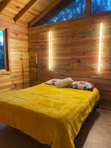 een slaapkamer met een geel bed in een houten muur bij CABAÑA LOS AZUFRES 