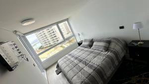 a bedroom with a bed and a large window at Dpto en Resort Laguna del Mar frente al mar 2D2B in La Serena