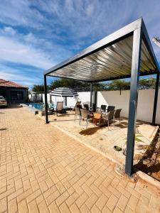 patio chiuso con sedie, tavolo e ombrellone di Legae garden home a Gaborone