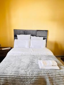 un letto con lenzuola bianche e una testiera grigia di Legae garden home a Gaborone