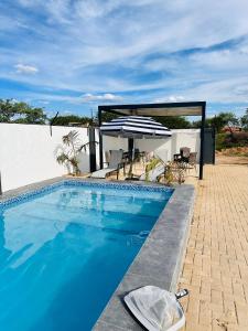 una piscina con ombrellone, tavolo e sedie di Legae garden home a Gaborone