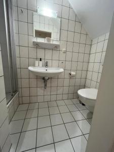 a white tiled bathroom with a sink and a toilet at Einzelzimmer mit Bad 14 in Meine