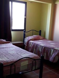 two beds in a room with a window at Hostal vivar in Calama