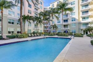 a swimming pool in front of a building with palm trees at Lantana Condo with Smart TV 11 Mi to Palm Beach! in Lantana
