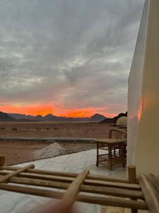a table and chairs on a patio with a sunset in the desert at Nasem rum in Wadi Rum
