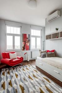 een slaapkamer met een bed en een rode stoel bij Luxurious Danubeside Apartment for 6 in Boedapest