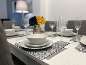 a table with a bowl and plates and wine glasses at The Heathers - Spacious 3 Bed, Home from Home in Burton in Burton upon Trent