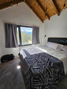 Un dormitorio con una cama y una ventana grande. en Tawa Wasi - Villa la Angostura, en Villa La Angostura