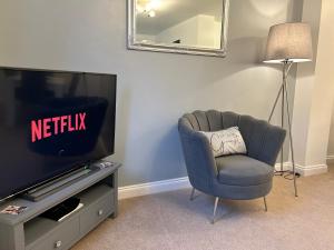 sala de estar con silla y TV en The Heathers - Spacious 3 Bed Home From Home, en Burton upon Trent