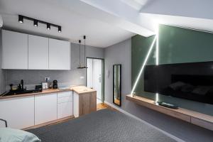 a kitchen with white cabinets and a large flat screen tv at Pistachio apart City center in Novi Sad +9 photos