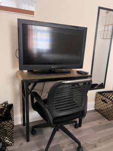 un monitor de ordenador en un escritorio con una silla negra en Simplicity Stays NOLA, en Nueva Orleans