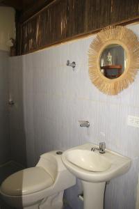 uma casa de banho com um lavatório, um WC e um espelho. em Hierba Buena Eco Hostel em El Zaino