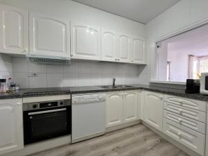 una cocina blanca con armarios blancos y fregadero en Precioso apartamento en la playa de Pals con piscina - Recinto Puig Sa Guilla, en Pals