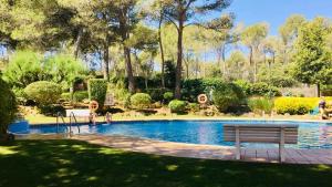 een zwembad met een bank in een park bij Precioso apartamento en la playa de Pals con piscina - Recinto Puig Sa Guilla in Pals