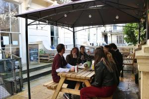 un grupo de personas sentadas en una mesa bajo un paraguas en Urbany Hostel London 18-40 Years Old, en Londres