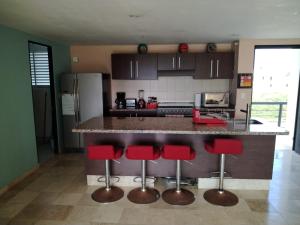 a kitchen with a counter with red bar stools at Perfectly located spacious apartment with 2 balconies in Ixtapa