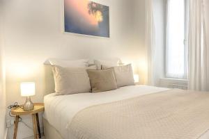 biała sypialnia z dużym łóżkiem z białymi poduszkami w obiekcie Le Nid Cosy -Au Cœur d'Orléans w Orleanie